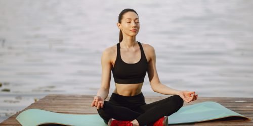 Pretty lady training in a summer park. Brunette doing yoga. Girl in a sportsuit.